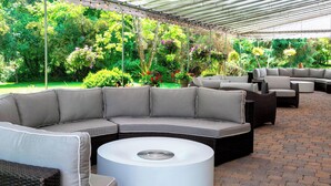 A covered outdoor seating area with a curved sectional sofa, a round coffee table, and multiple chairs. - Delta Hotels by Marriott Basking Ridge (Basking Ridge)