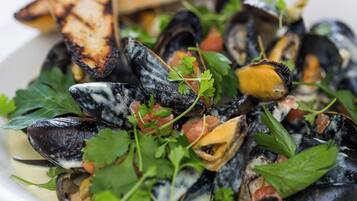 A dish of mussels with grilled bread and fresh herbs.