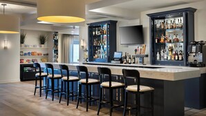 A bar area with a marble countertop, black bar stools, and a variety of liquor bottles. - Delta Hotels by Marriott Basking Ridge (Basking Ridge)