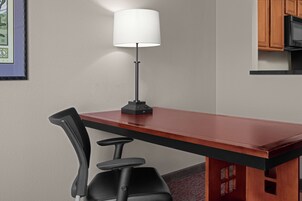 A modern kitchen with a wooden table, black chairs, and a white lamp.