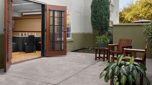 An open door leading to a room with a table and chairs, a potted plant, and a wooden bench outside.