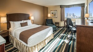 Une chambre d’hôtel avec un grand lit, un bureau, une chaise et une vue sur la ville.