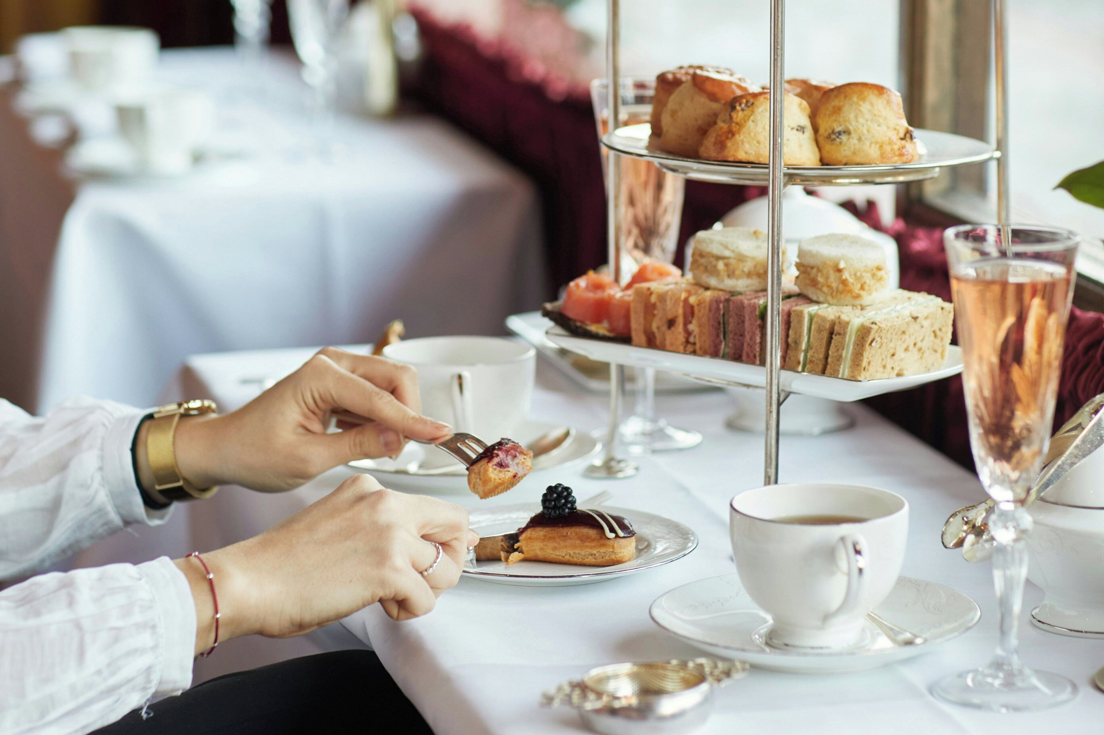 A table with a tiered dessert stand, a cup of coffee, and a glass of champagne.