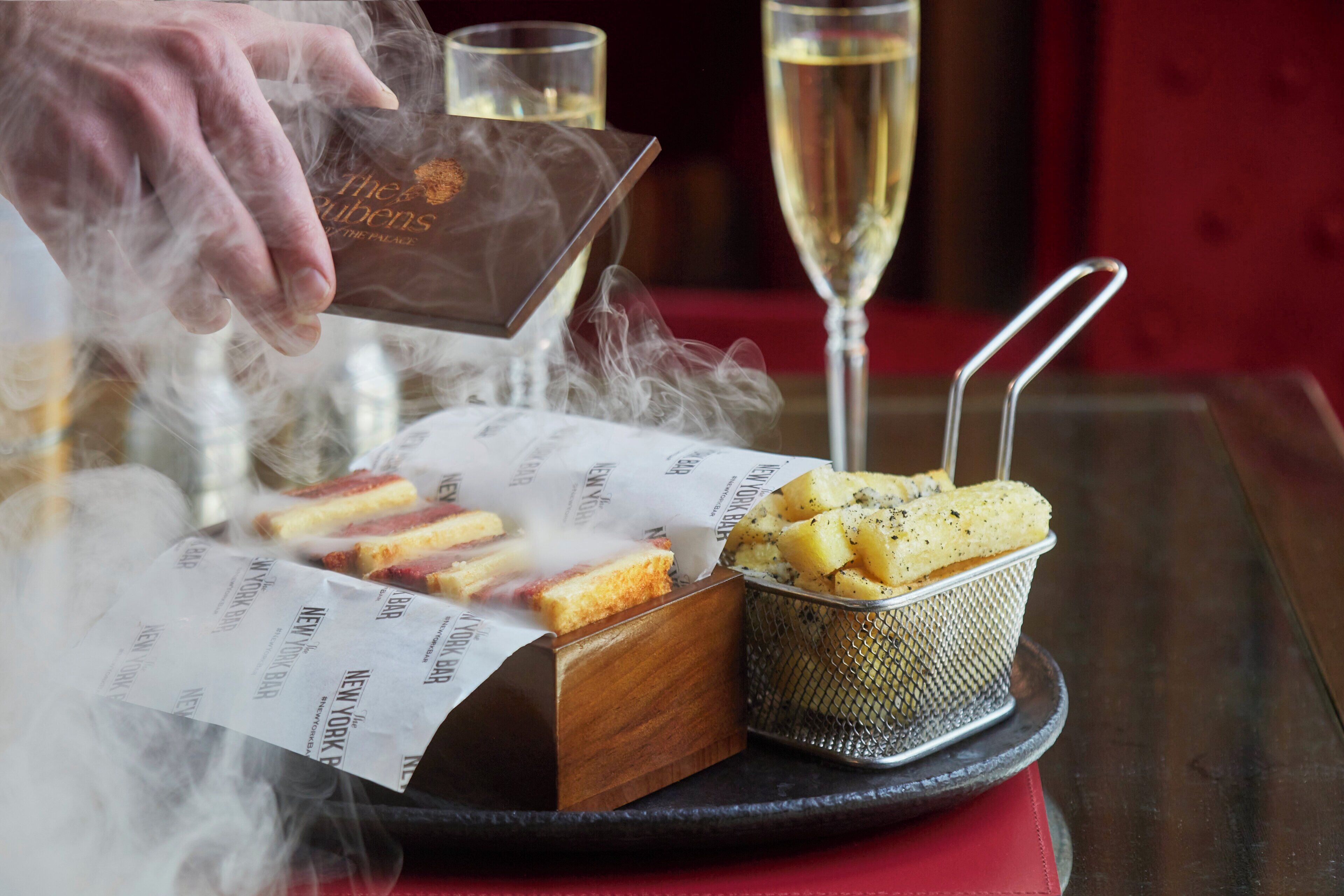 Ett bricka med en låda varma korvar, en korg med pommes frites och ett glas champagne.