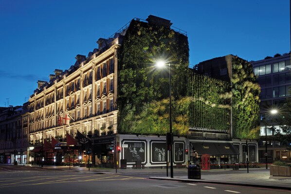A historic building with a modern green facade, a street-level bar, and a well-lit intersection.