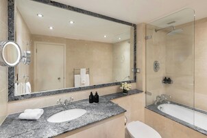 Ein modernes Badezimmer mit einer Granit-Arbeitsplatte, zwei Waschbecken, einem großen Spiegel und einer Duschkabine.