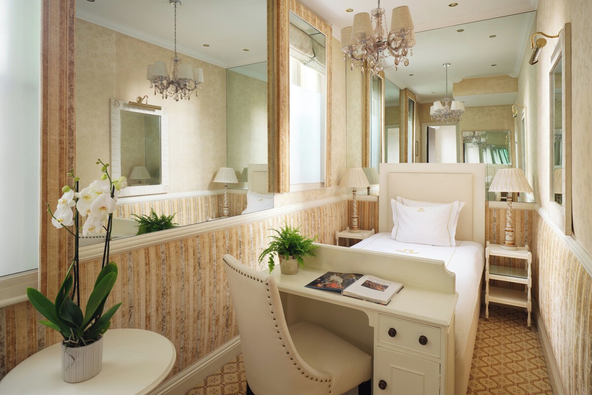 Une chambre d’hôtel avec un grand miroir, un bureau, une chaise et un lit.