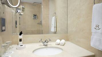 A bathroom with a sink, mirror, towel rack, and toiletries.