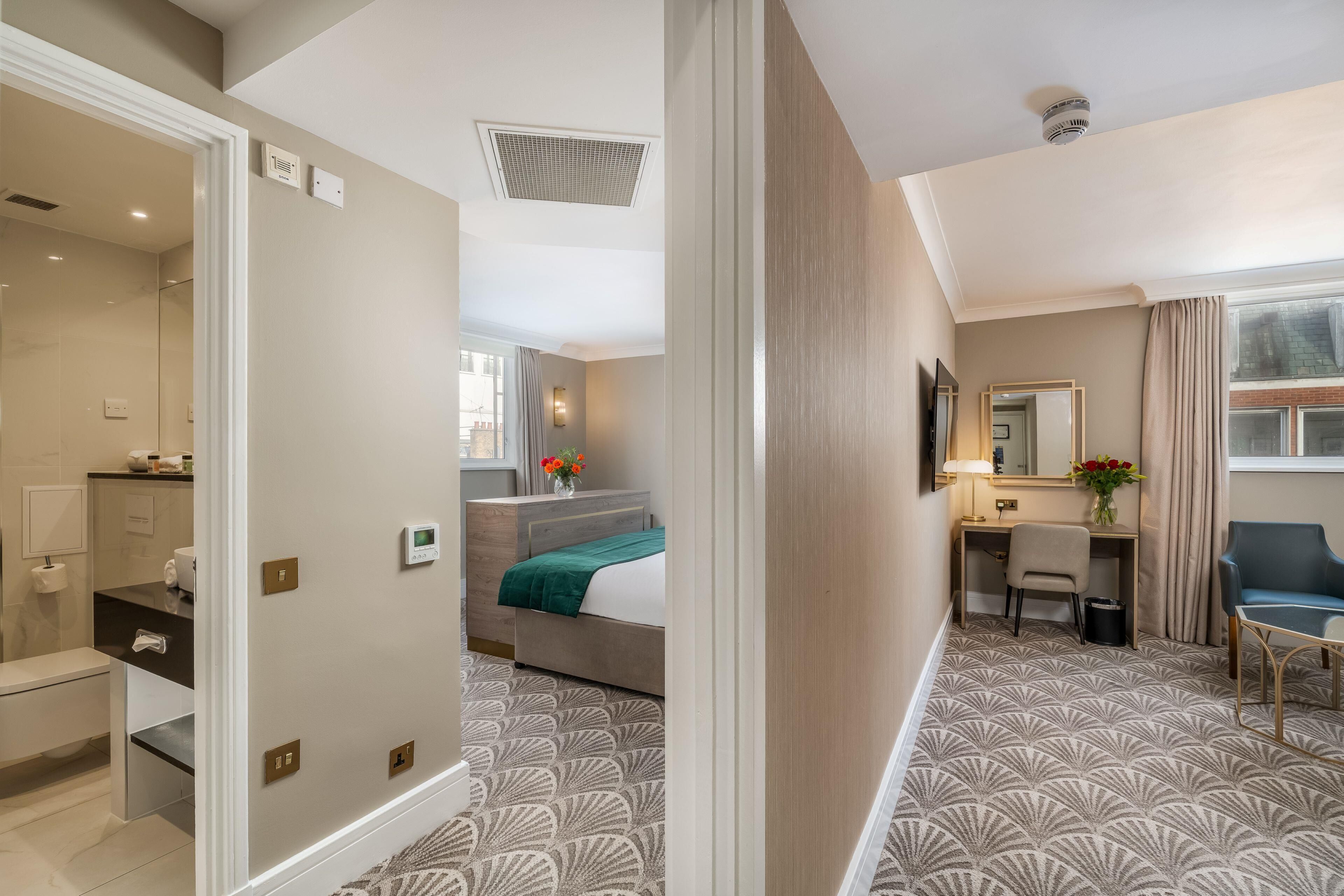 A hotel room with a bed, a desk, a chair, a bathroom, and a shower.