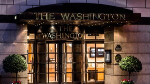 The entrance to The Washington hotel with a prominent sign, double doors, and two potted plants. - Washington Mayfair Hotel (London)