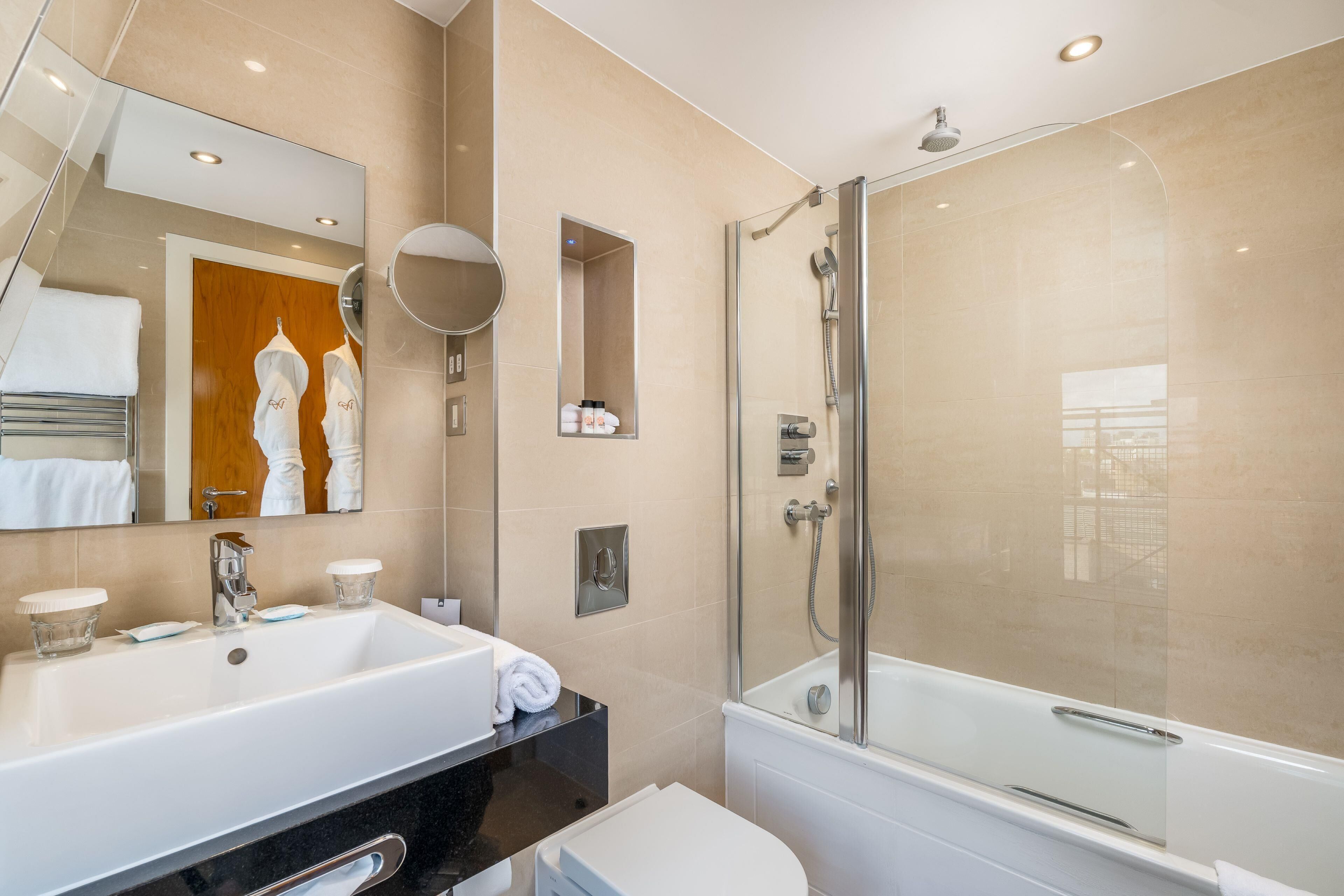 A modern bathroom with a large sink, mirror, and glass-enclosed shower.
