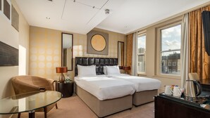 A hotel room with a double bed, a glass table, a chair, a desk, and a view of the city. - Washington Mayfair Hotel (London)