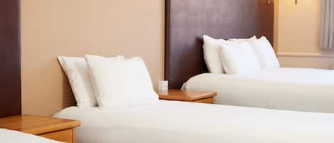 Una habitación de hotel con dos camas, mesitas de noche de madera y lámparas fijadas a la pared.