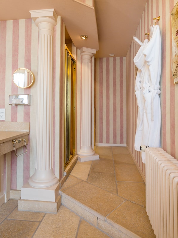 Une salle de bain avec des murs à rayures, un lavabo, un miroir et un porte-serviettes.