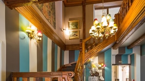 A wooden staircase with a chandelier, striped walls, and a door in the background. - Hostellerie de la Pommeraie by Popinns (Sélestat)