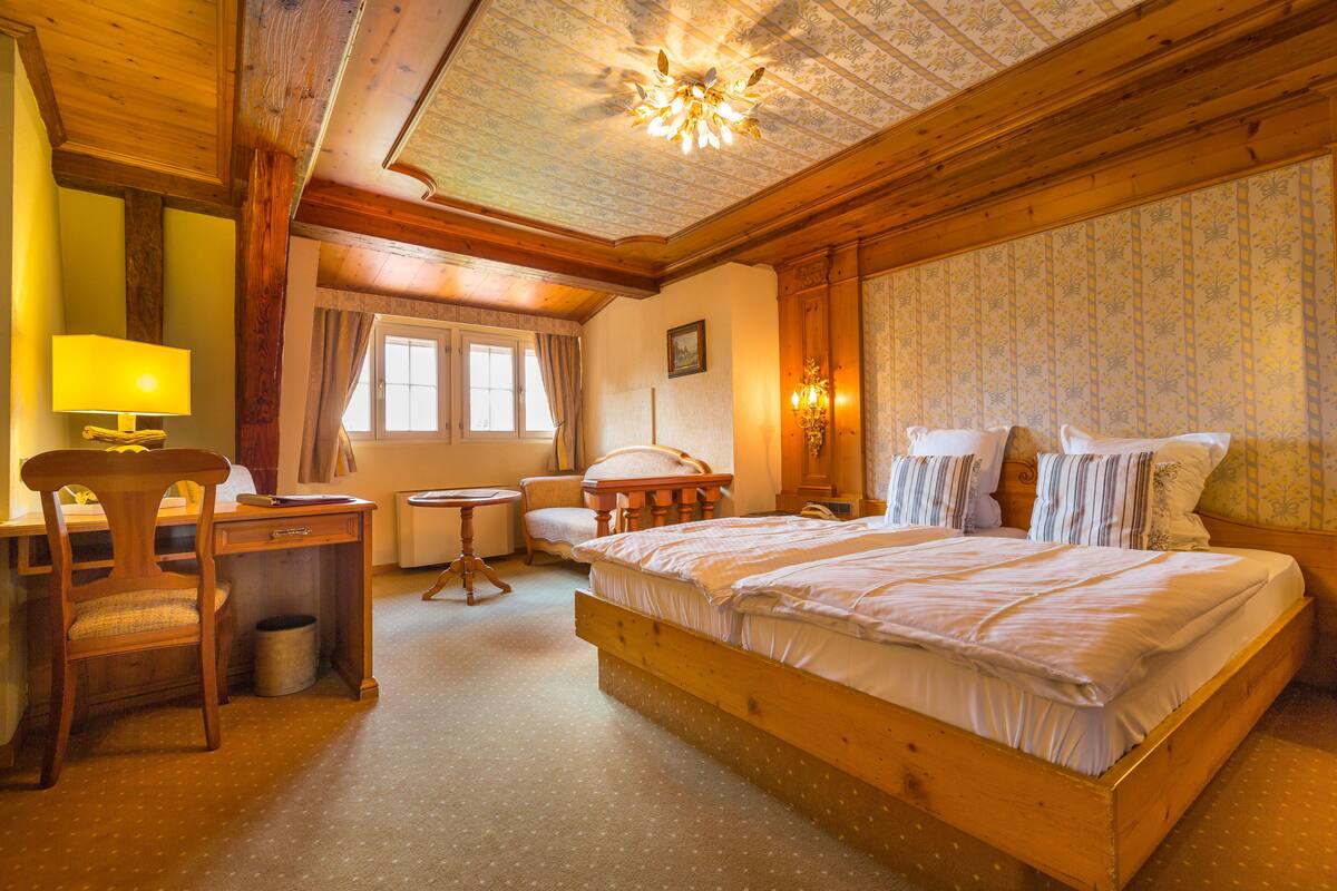 Ein gemütliches Zimmer mit einem hölzernen Bett, einem Schreibtisch und einem Stuhl.