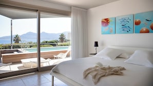 A bedroom with a large bed, a view of a pool and mountains, and artwork on the wall. - La Villa Calvi (Calvi)