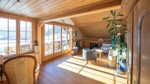 Une cabane en bois spacieuse, dotée de grandes fenêtres, d’un coin salon confortable et offrant une vue sur les montagnes.