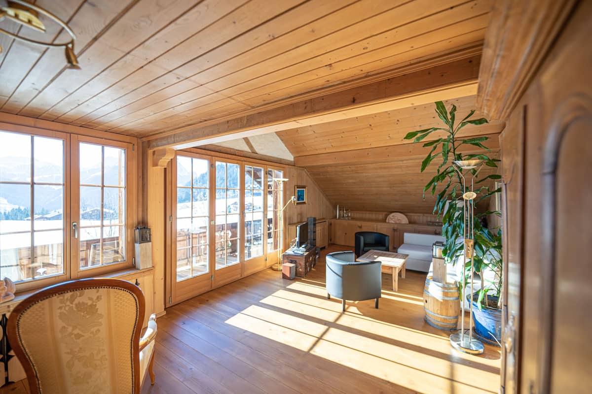 A spacious wooden cabin with large windows, a cozy seating area, and a view of the mountains.