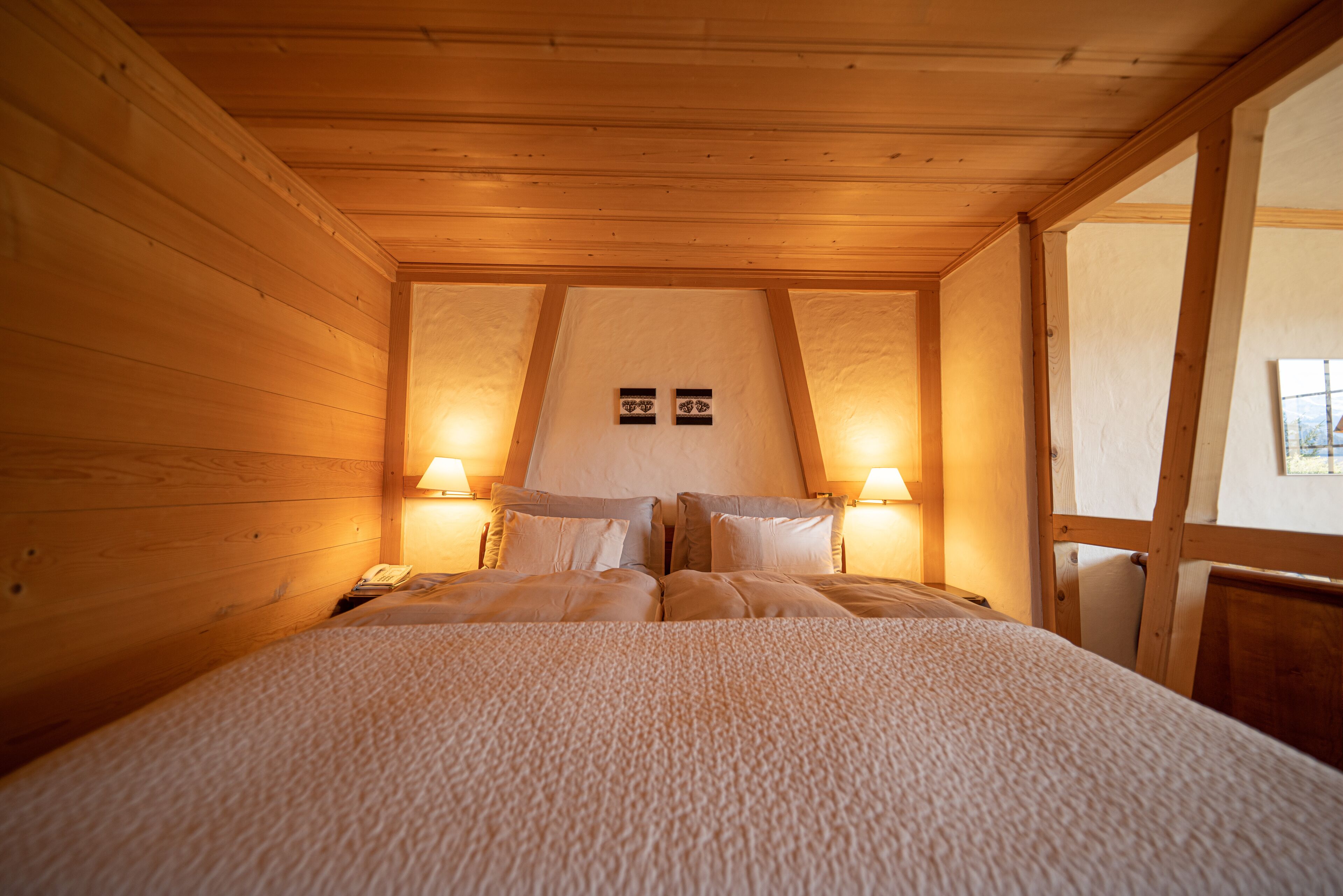 Un dormitorio de cabaña de madera con cama, dos lámparas de noche y un reloj en la pared.