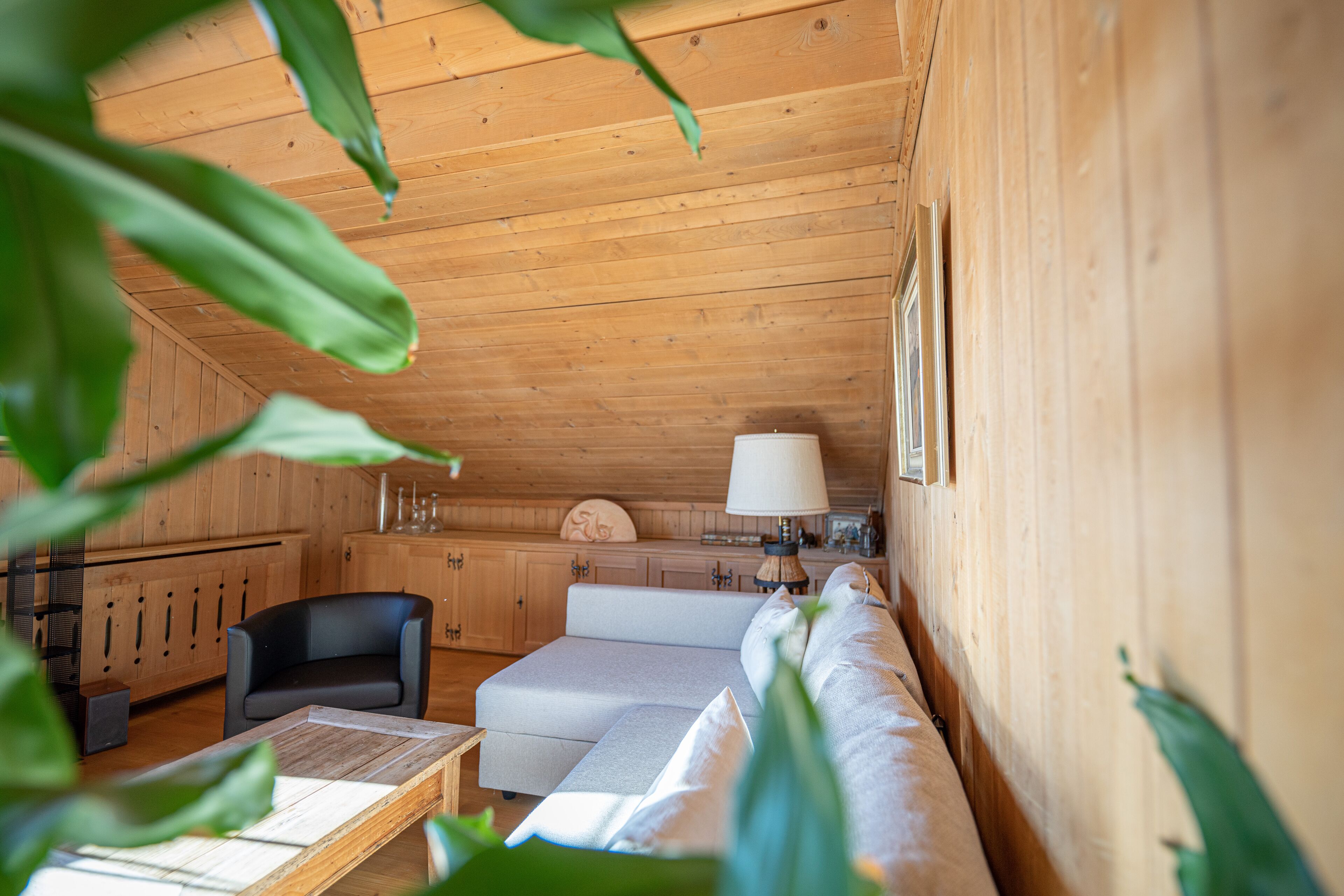 Acogedor interior de cabaña de madera con sofá, una mesa y una lámpara.