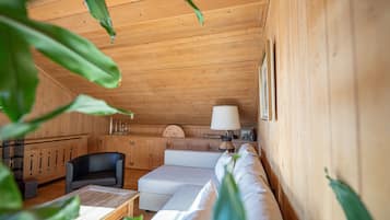Acogedor interior de cabaña de madera con sofá, una mesa y una lámpara.