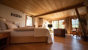 Une chambre spacieuse avec un grand lit, un plancher en bois, un bureau et une chaise.