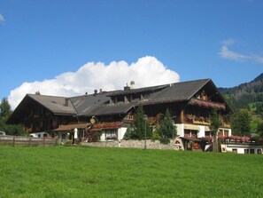 A traditional chalet-style building with a sloped roof, wooden exterior, and flower boxes on the balconies.