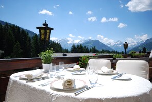 A table set for two with a mountain view, a lamp, and a potted plant.