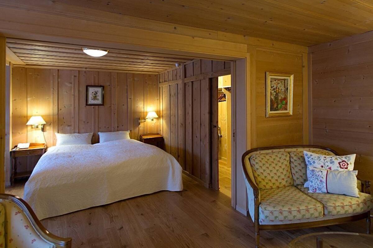 A cozy room with a bed, a sofa, and two bedside tables with lamps.