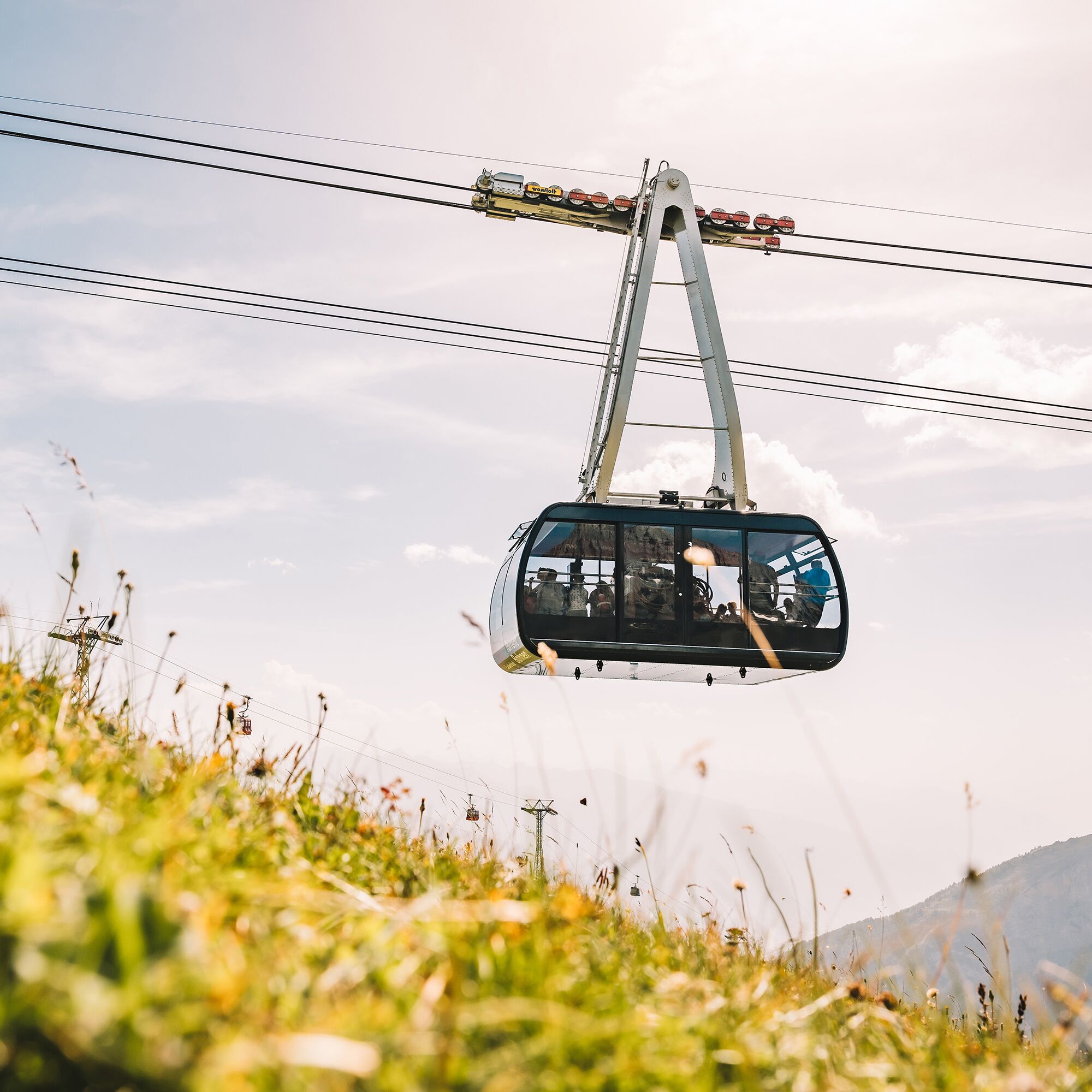 A cable car suspended by cables against a clear sky.