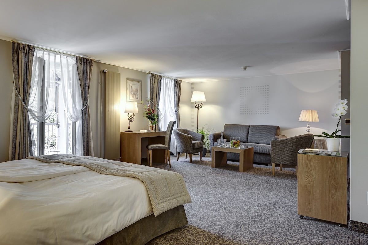 Une chambre d’hôtel avec un grand lit, un bureau, une chaise, un canapé et une armoire.