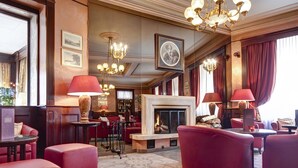 A spacious lobby with a fireplace, red upholstered seating, and a patterned carpet. - Résidence Les Sources Des Alpes (Leukerbad)