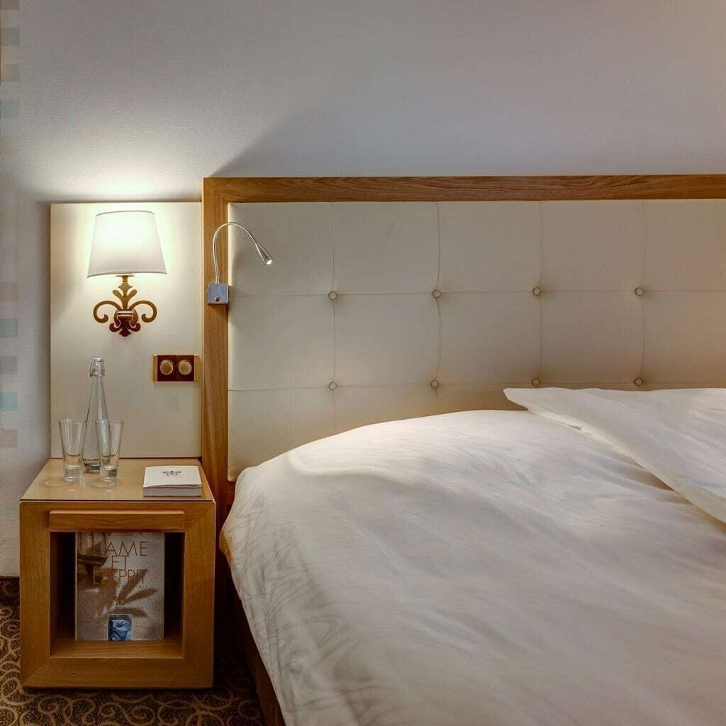 A hotel room with a bed, a nightstand with a lamp, and a framed picture.