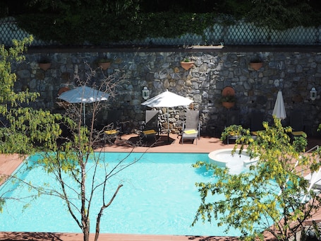 Una piscina al aire libre, sombrillas, sillones reclinables de piscina