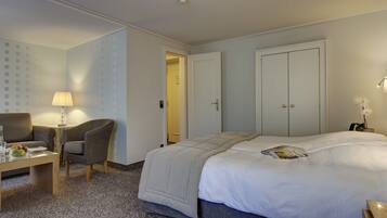 Une chambre d’hôtel avec un lit, un canapé, une petite table avec une lampe et une chaise.