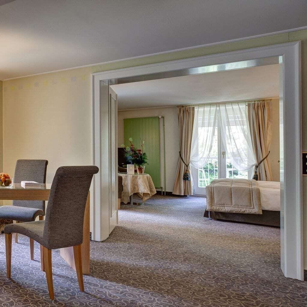 Ein Hotelzimmer mit Essbereich, einem Bett und Blick ins Freie.