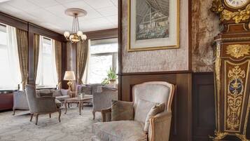 A spacious room with a large armchair, a grand clock, and a framed picture on the wall.