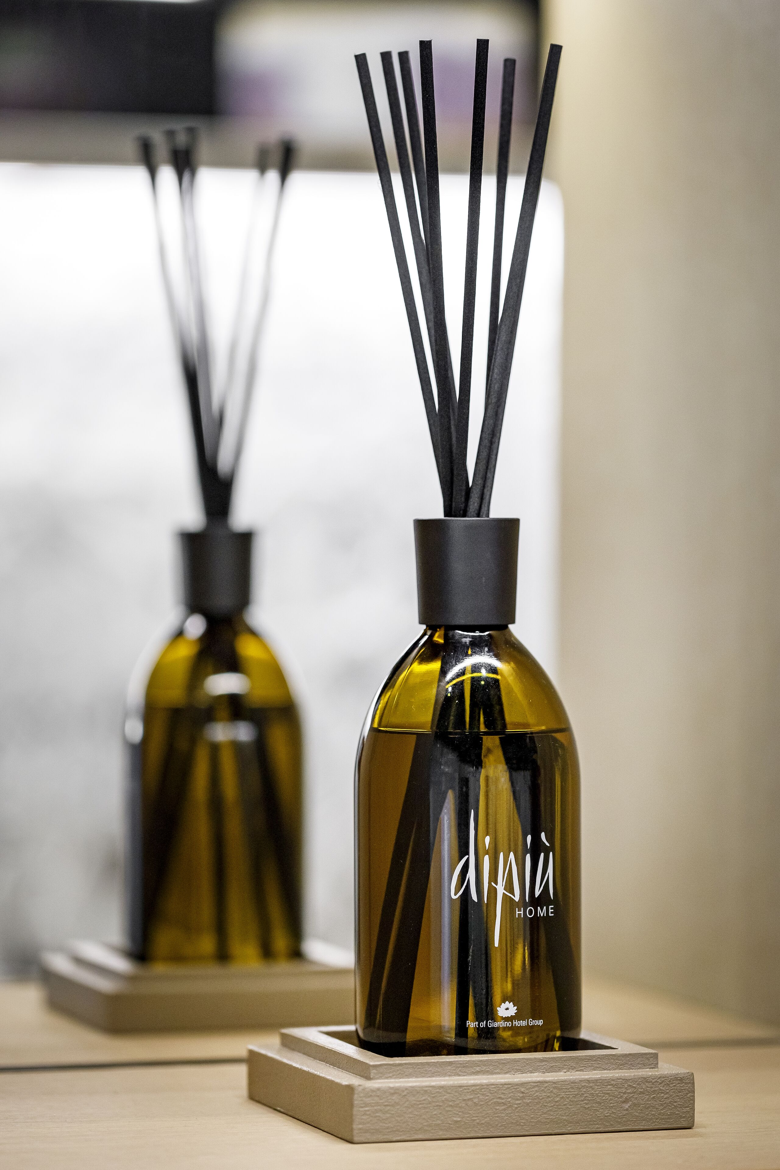 Two bottles of dipuì home fragrance on a wooden surface.