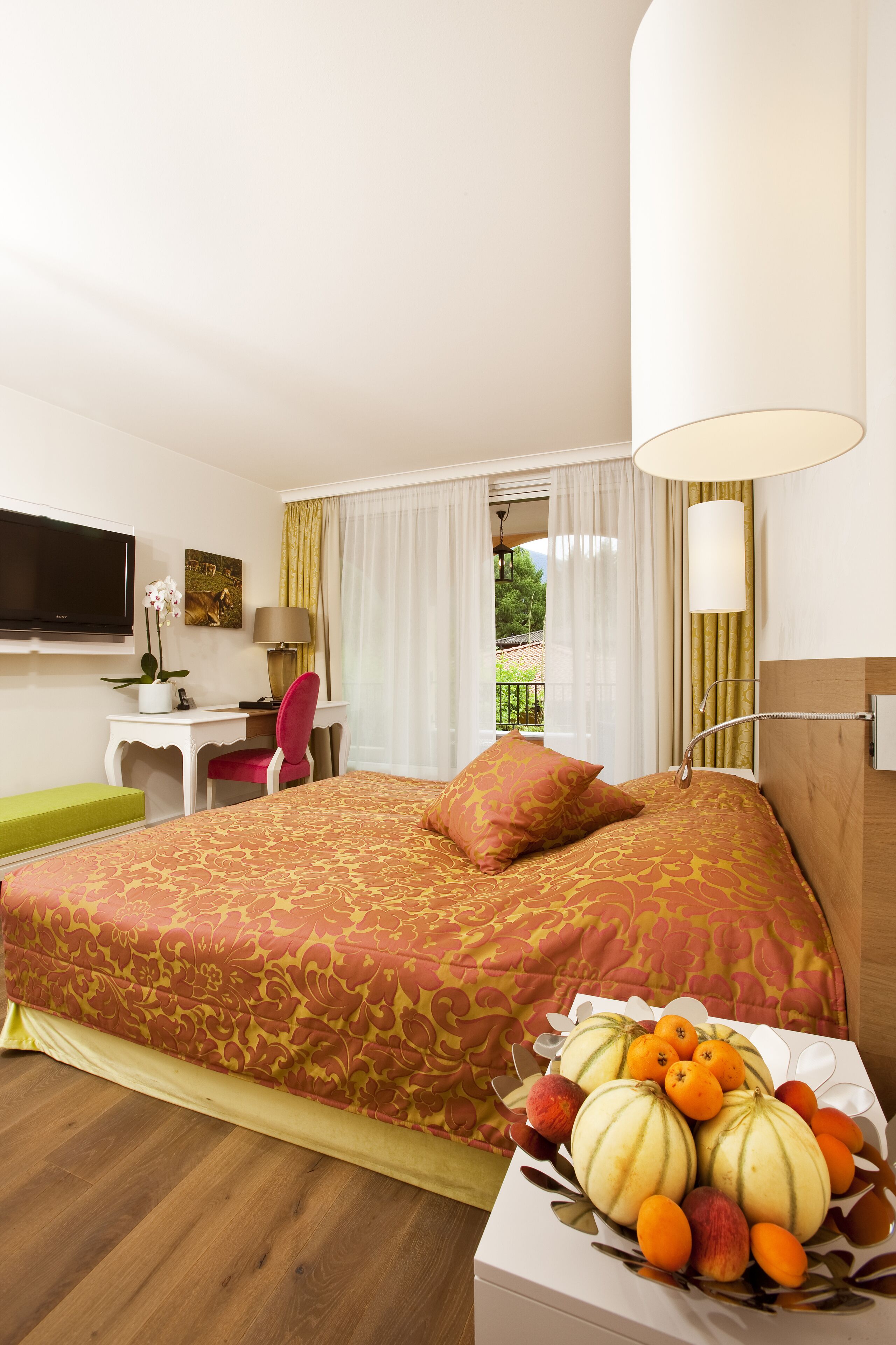 Un cuarto de hotel con una cama grande, un escritorio, un televisor y vistas al exterior.