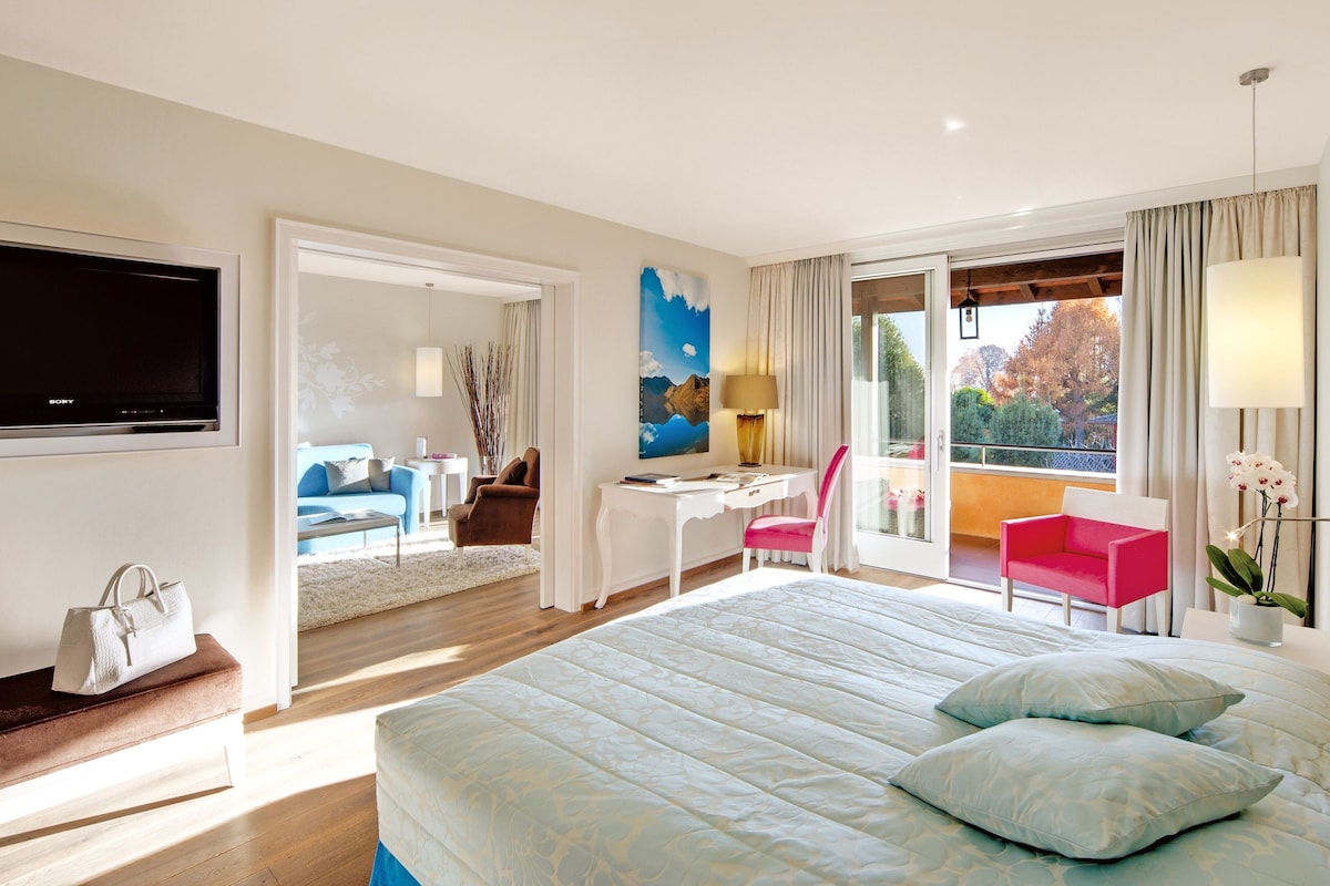 Habitación de hotel con una cama grande, un escritorio, una silla, televisión y balcón con vistas.