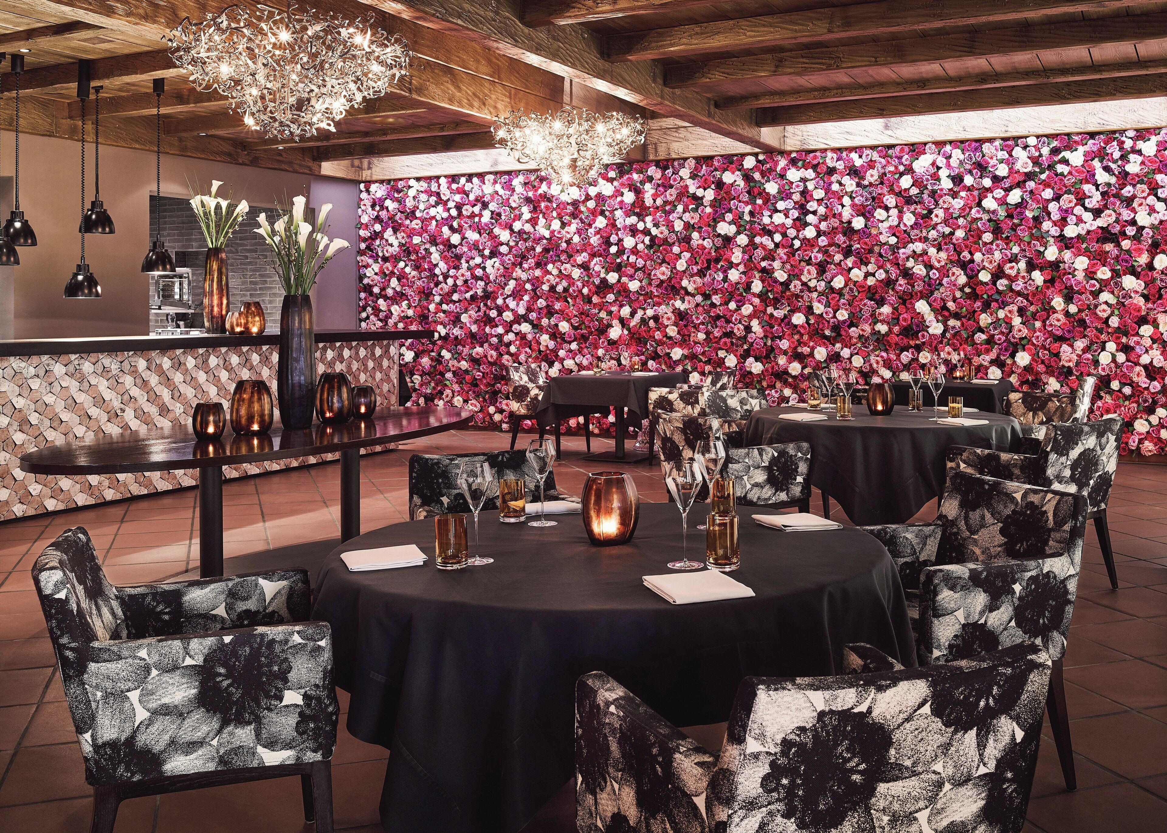 Un restaurant avec des tables rondes, des nappes noires et des chaises à motifs floraux.