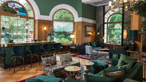 A spacious lounge area with a bar, comfortable seating, and large windows offering views of greenery. - Hotel Walther (Pontresina)
