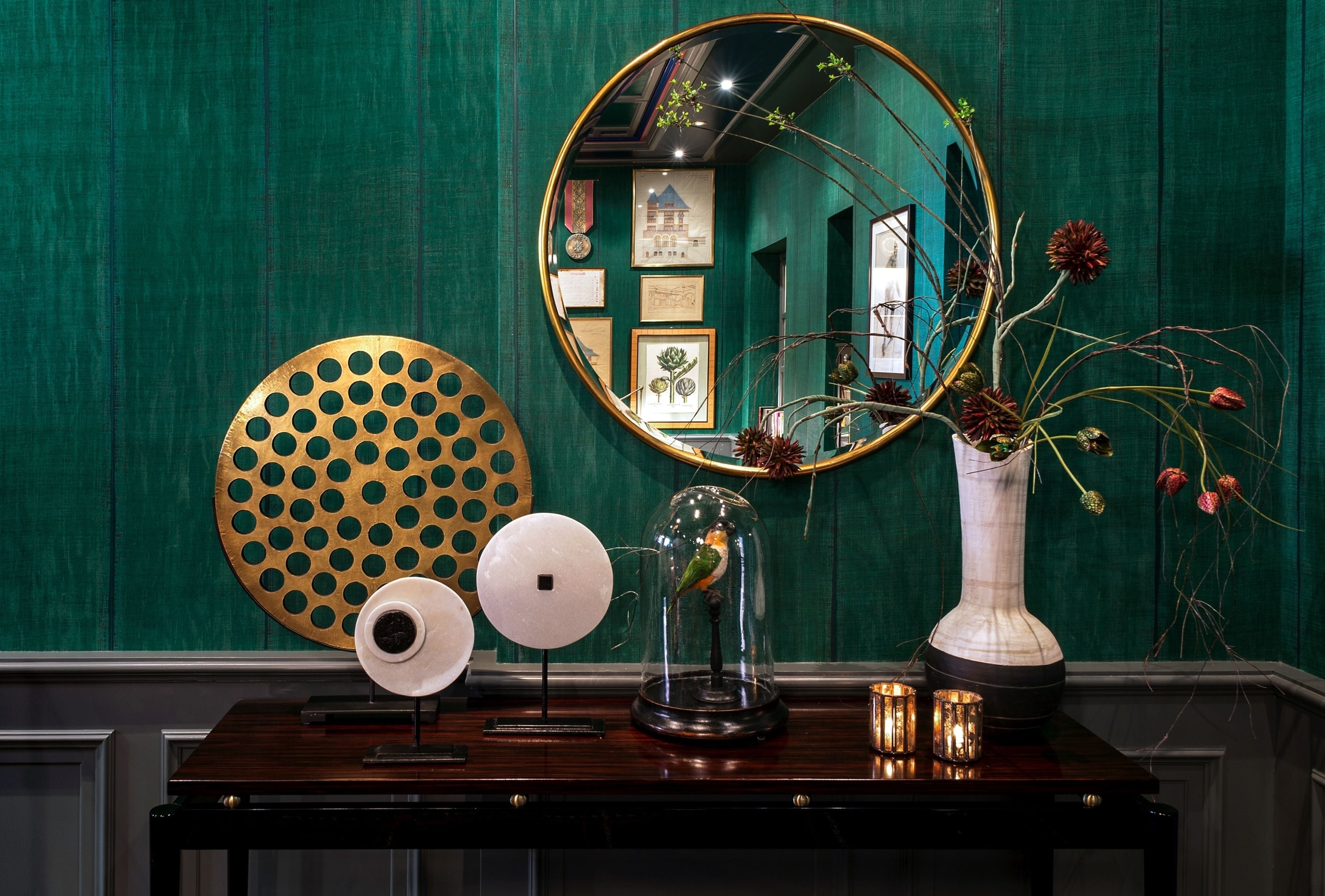 A wooden table with a mirror, a vase with flowers, a globe, and a decorative plate.