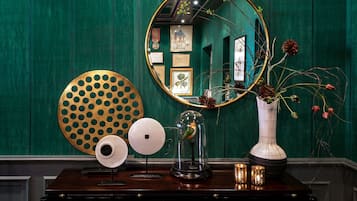 A wooden table with a mirror, a vase with flowers, a globe, and a decorative plate.