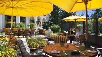 An outdoor patio with yellow umbrellas, wooden tables, and striped chairs.