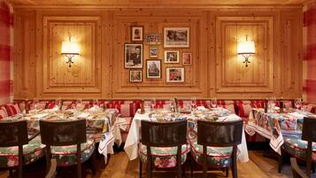 Ein Restaurant mit Holzwänden, gerahmten Bildern und gedeckten Tischen, komplett mit Weingläsern und Tellern.