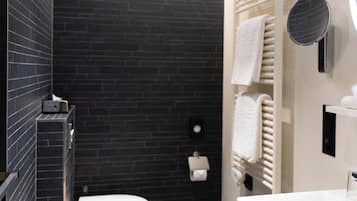 A modern bathroom with a black tiled wall, a white toilet, a white sink, and a towel rack.