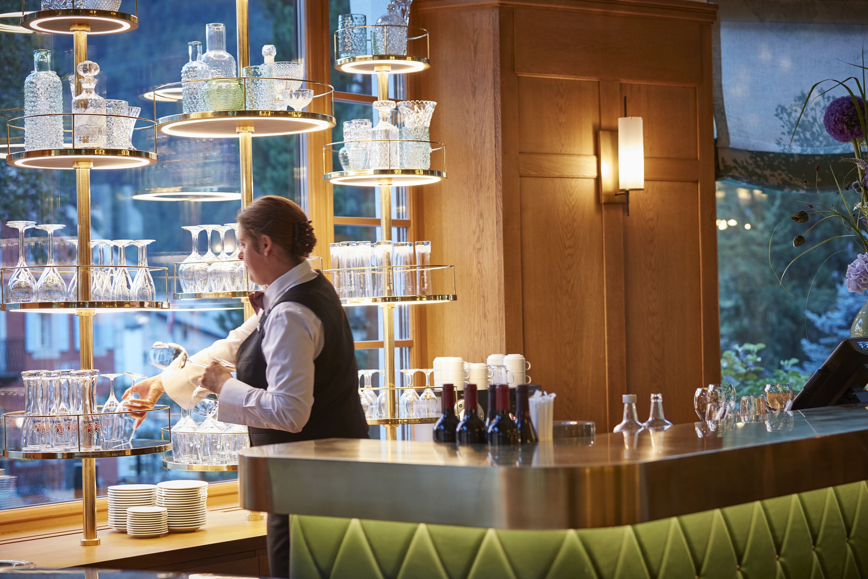Een bar met een barman, glazen en flessen.