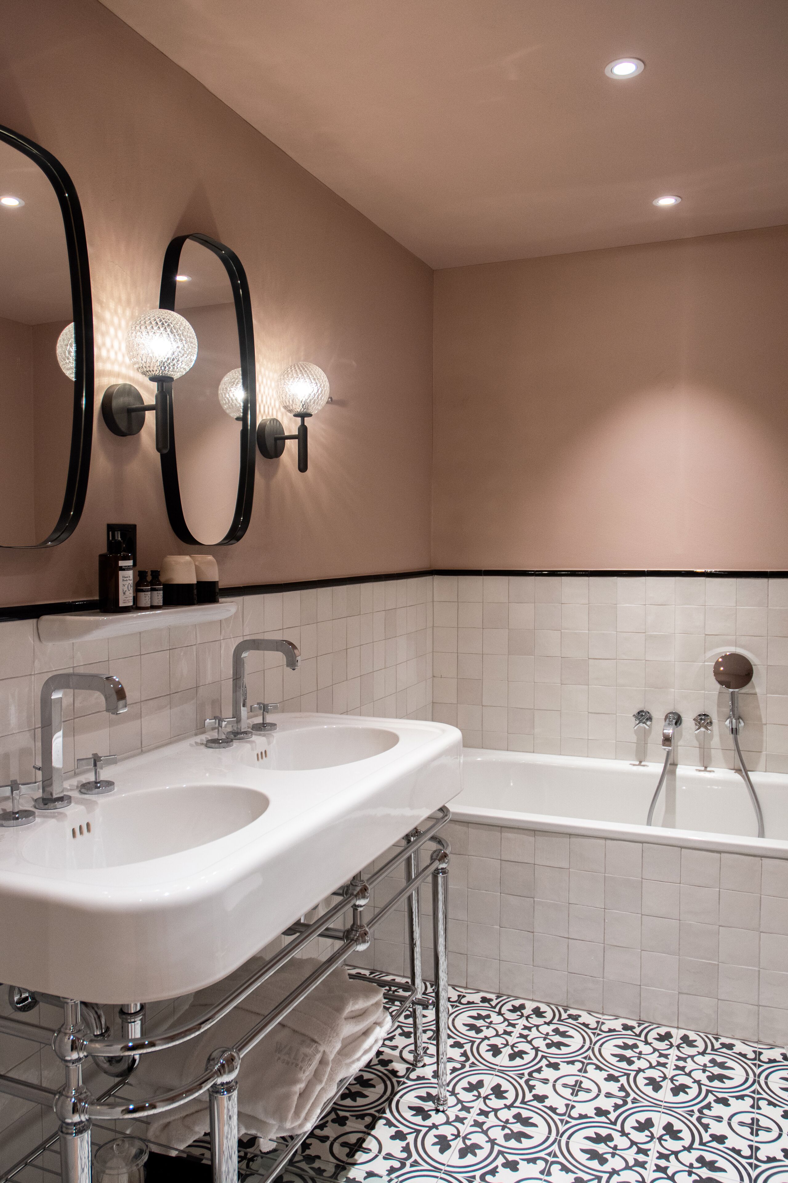 Un baño moderno con dos lavamanos, una bañera y un espejo grande con iluminación.
